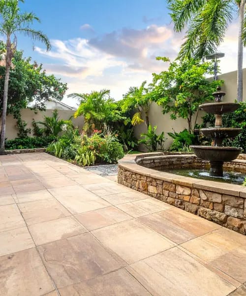 Lush garden with fountain and pathway.